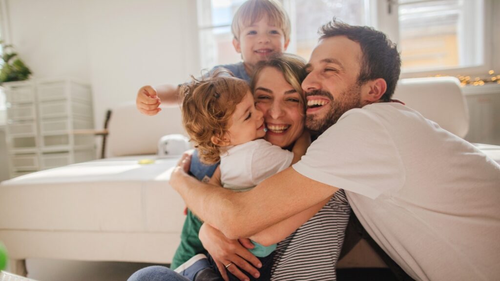 Happy family hugging on the couch in a bright living room, capturing a candid at-home moment.